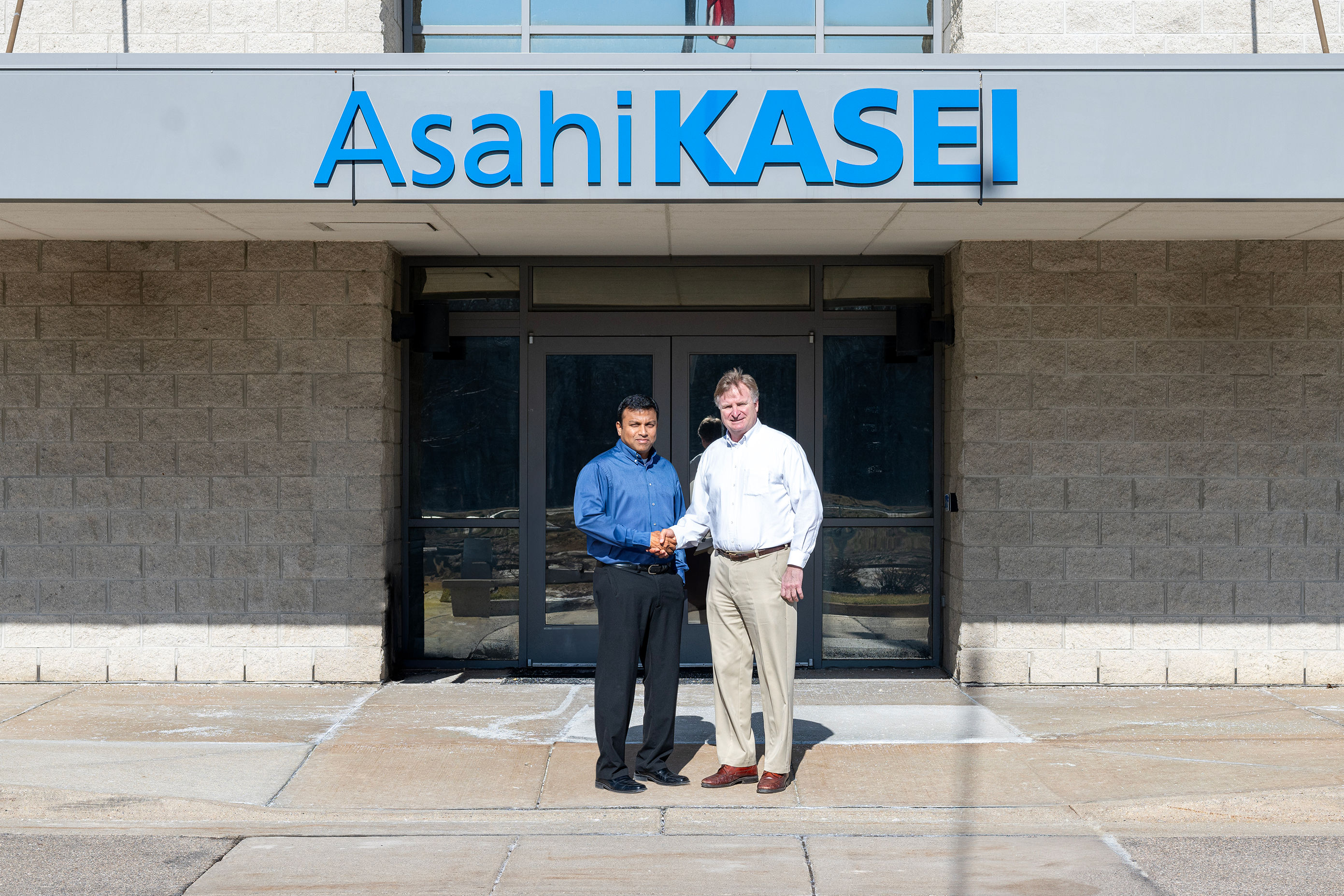 Phani Nagaraj (left) and Todd Glogovsky (right) standing in front of Asahi Kasei Plastics North America in Fowlerville, Michigan