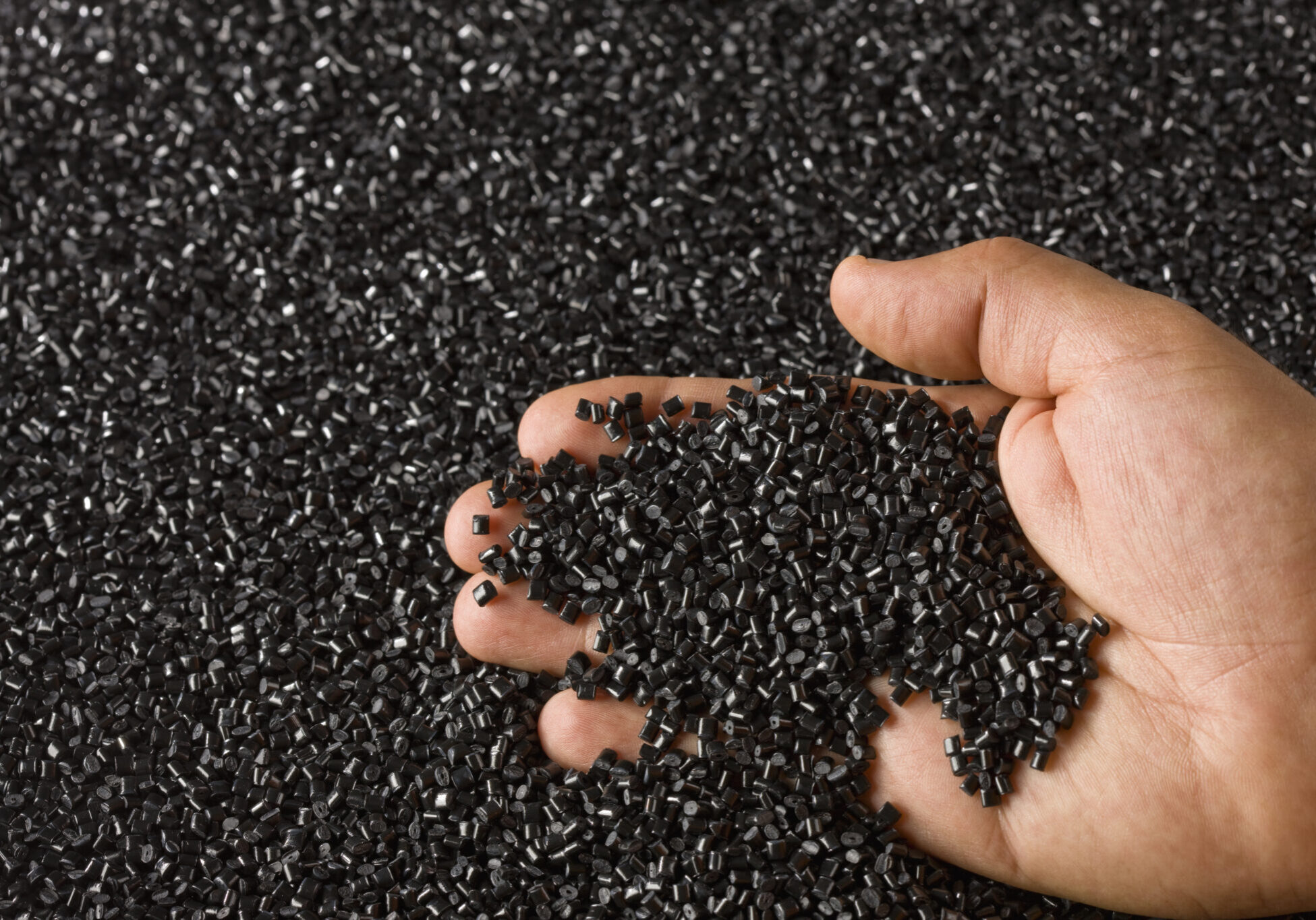 Plastic Black Resin Pellets in a Holding Hand
